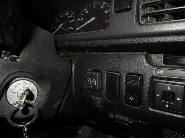 Кнопка переключения и индикации режимов работы ГБО в салоне Mazda Capella в стандартной заглушке справа от руля
